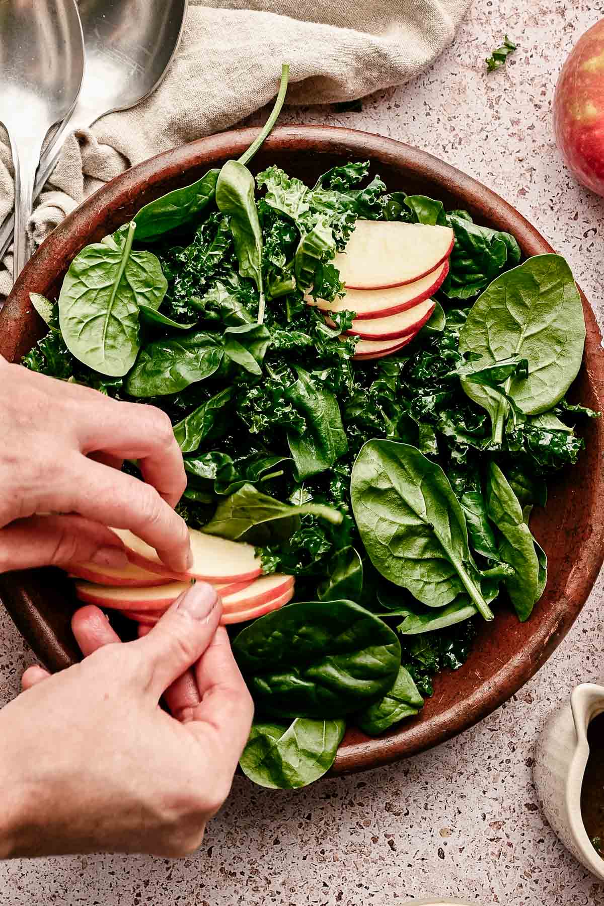 Adding sliced apples to the kale and spinach.