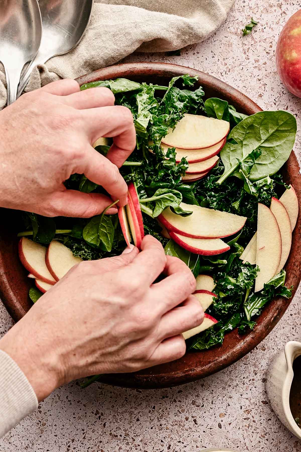 Adding sliced apples to the kale and spinach.
