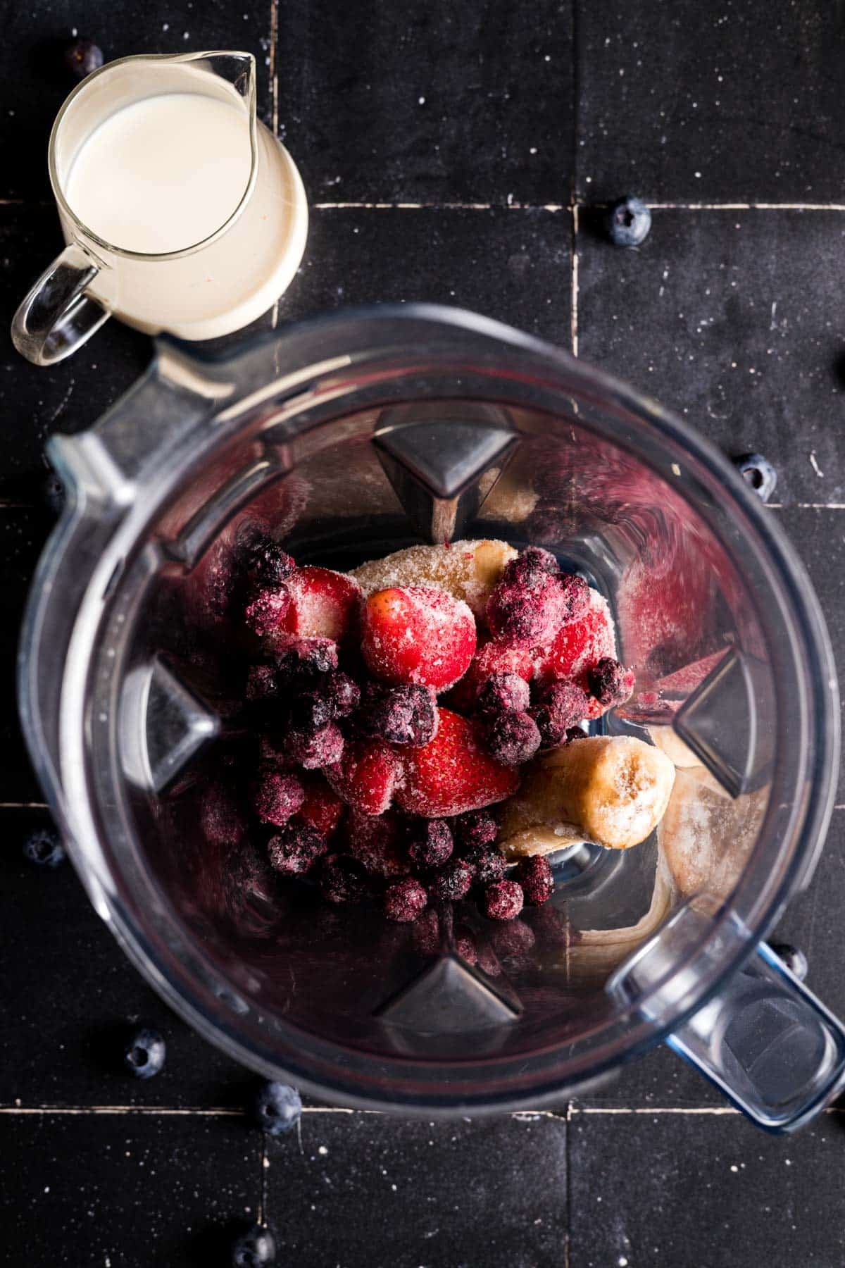 Frozen fruit added to a high speed blender pitcher.
