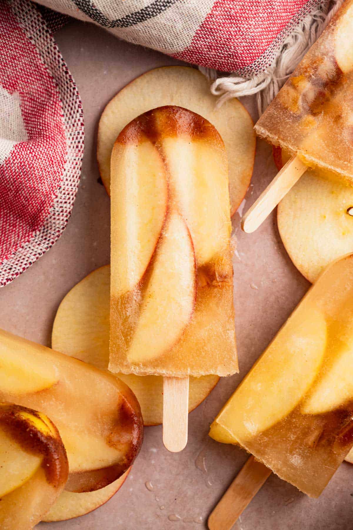 Caramel apple ice pops on a light pinkish tan counter.